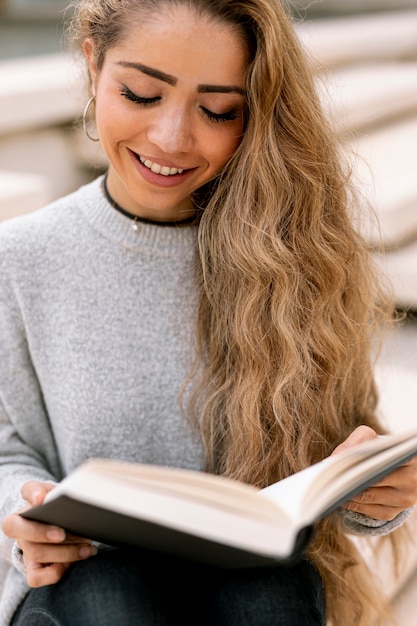 Бесплатное фото Белокурая женщина читая книгу снаружи