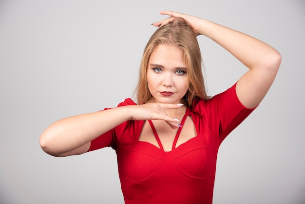 Foto gratuita donna bionda in abito rosso che guarda l'obbiettivo.