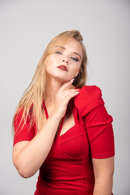 Free photo blonde woman in red outfit touching her chin.