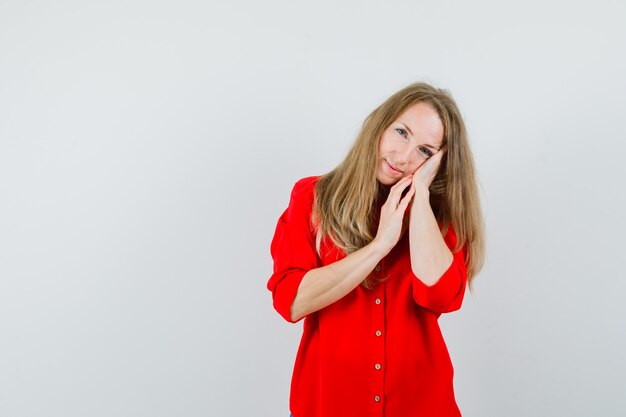 Blonde woman in red shirt leaning on palm as pillow and looking elegant ,