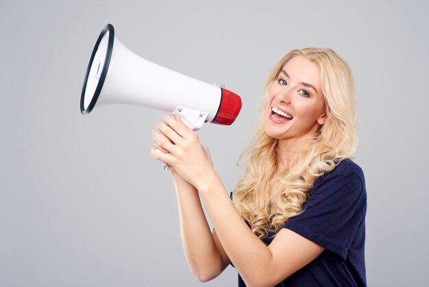 Blonde woman screaming through the loudspeaker