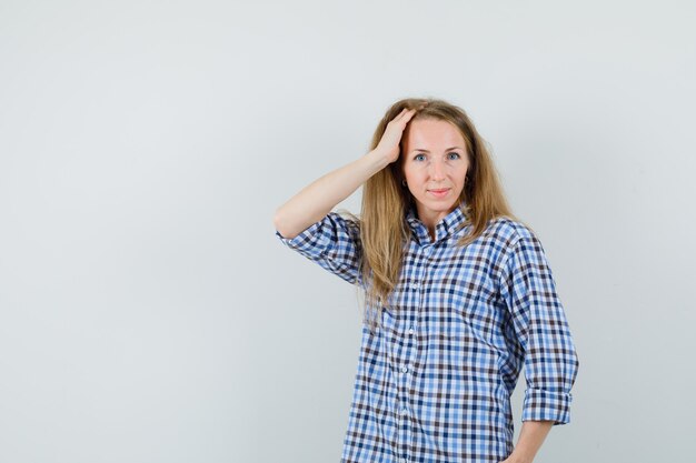 Blonde woman in shirt holding hand on head and looking alluring ,