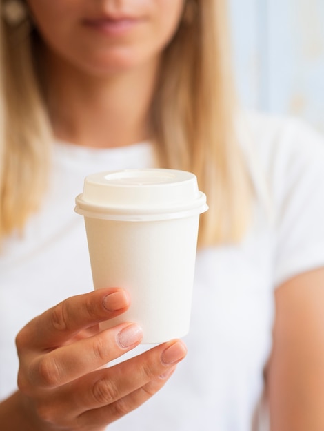 Foto gratuita donna bionda che mostra una tazza di caffè di plastica