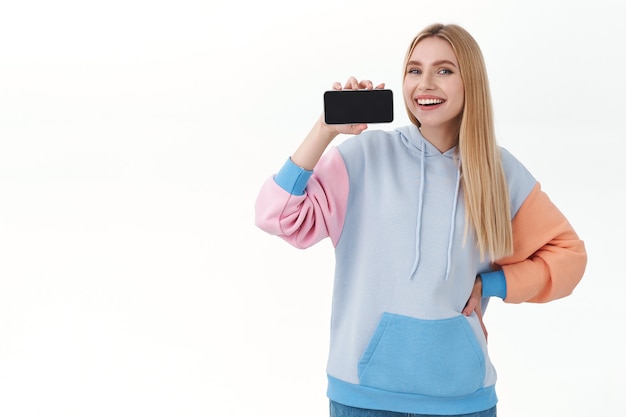 Free photo blonde woman showing smartphone screen