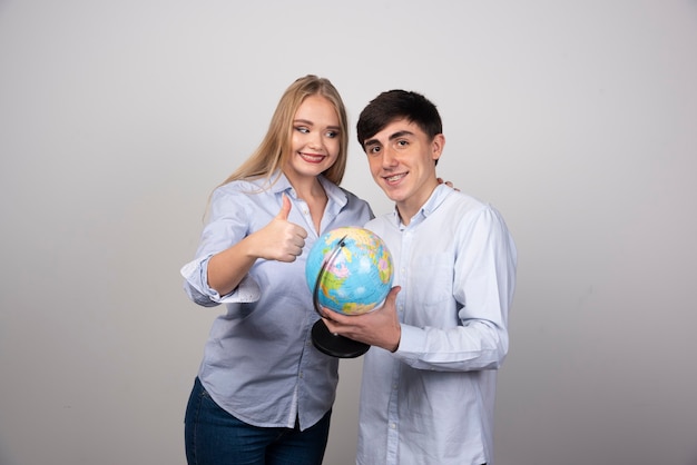 Blonde woman showing thumb up and guy holding earth globe