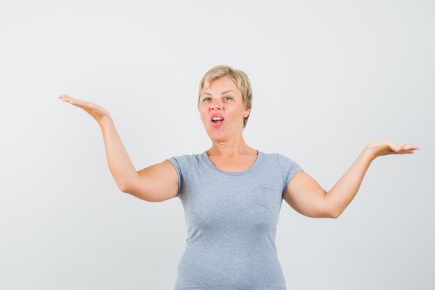 Blonde woman shrugging her shoulders in light blue t-shirt and looking annoyed. front view.