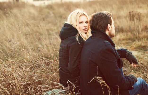 Blonde woman sitting with her partner on the meadow