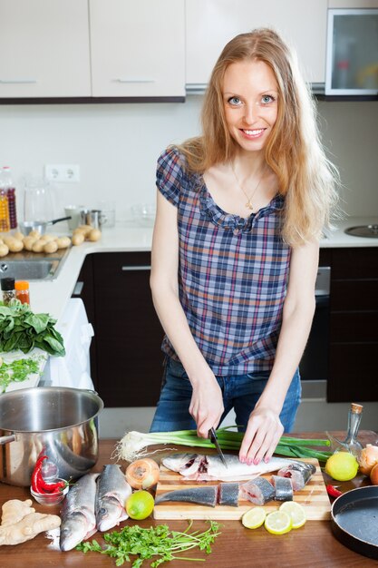 blonde woman slicing raw fish