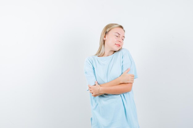 Blonde woman standing arms crossed, keeping eyes closed