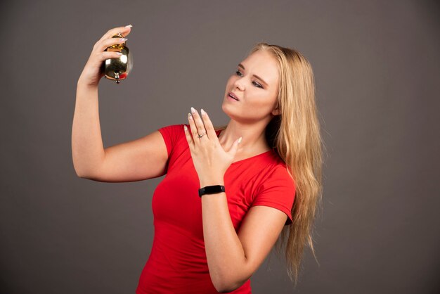 Blonde woman standing on black wall with clock.