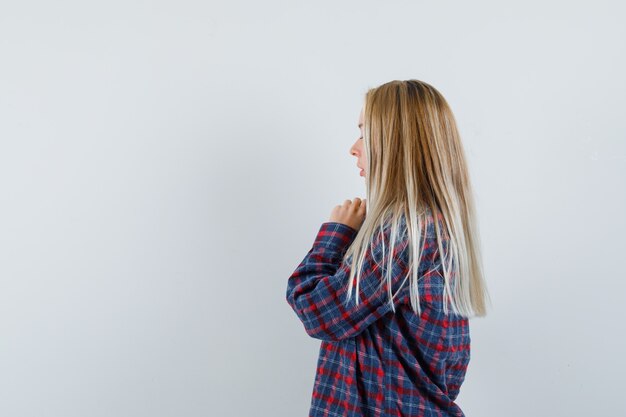 Blonde woman standing in prayer pose in checked shirt and looking focused. front view.