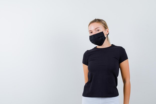 Blonde woman standing straight and posing in black t-shirt