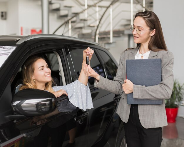 Blonde woman taking keys from a  car dealer