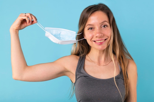 Free photo blonde woman taking off her medical mask