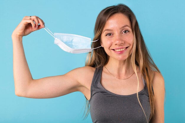 Blonde woman taking off her medical mask