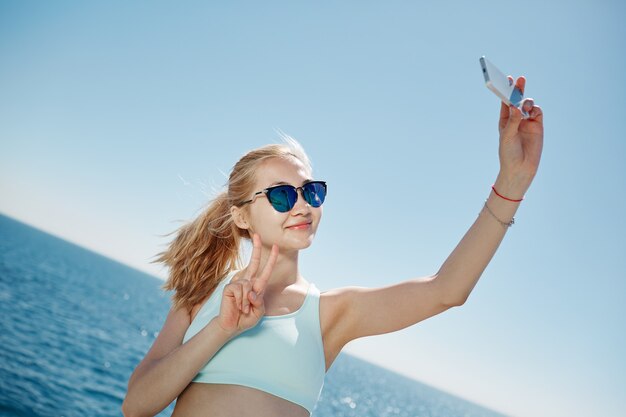 금발의여자가 해변에서 selfie를 복용