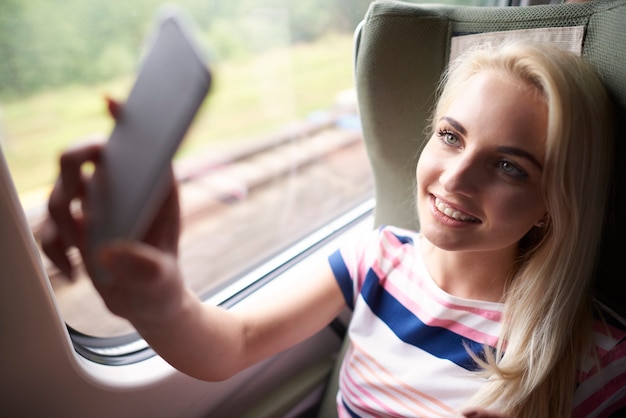 Foto gratuita donna bionda che cattura selfie in treno