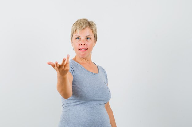 水色のTシャツで何かを説明しようとしている金髪の女性と真剣に見えます。正面図。