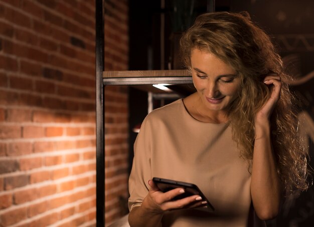 Foto gratuita donna bionda che guarda qualcosa sul suo telefono a casa