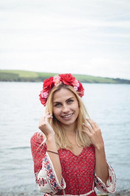 Blonde woman wearing a flower tiara standing near a river