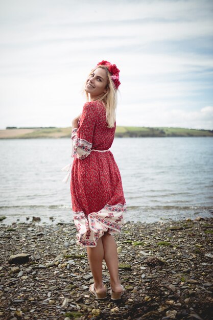 Blonde woman wearing a flower tiara standing near a river