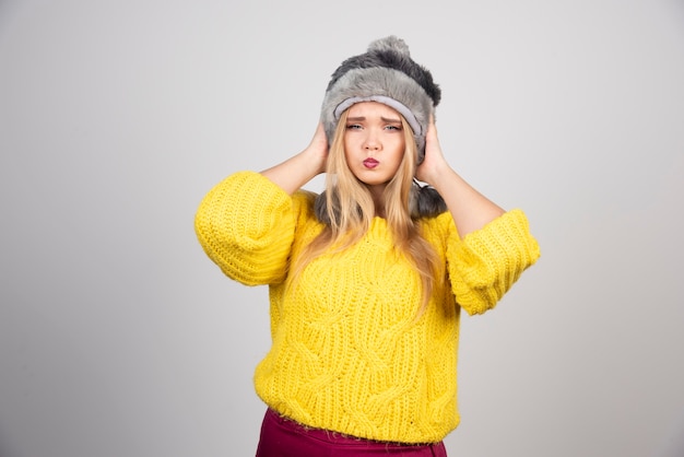 Блондинка женщина в зимней шапке позирует.
