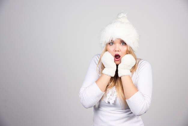 Blonde woman in winter outfit acting shocked.