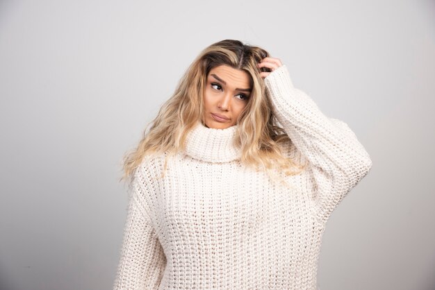 Blonde woman in winter outfit scratching her hair. 