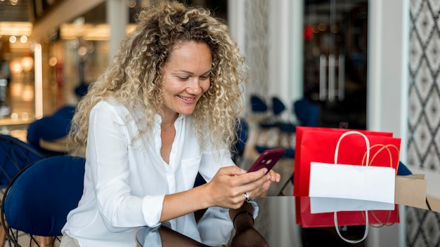 Free photo blonde woman with curly hair texting