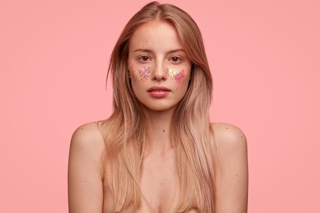 Blonde woman with glitter on face posing