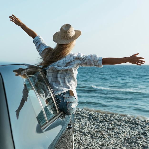 Blonde woman with hat standing out of car window