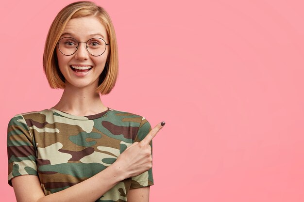 Blonde woman with round glasses and camouflage T-shirt