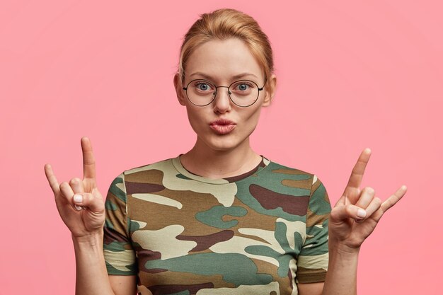 Blonde woman with round glasses and camouflage T-shirt