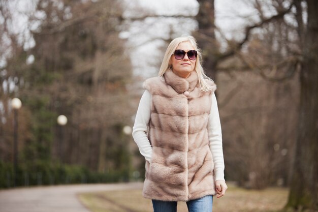 Blonde woman with sunglasses walking in the park