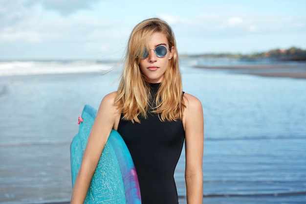 Free photo blonde woman with surfboard on beach