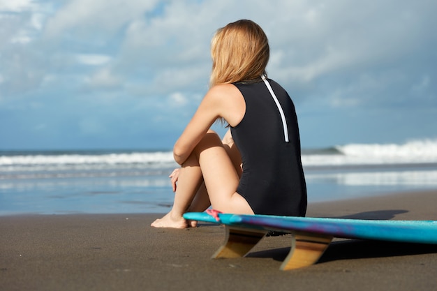 Блондинка с доской для серфинга на пляже