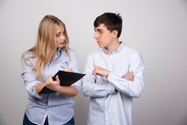 Blonde woman writing in folder and looking at brunette guy model .