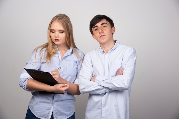 Blonde woman writing in folder and standing near brunette guy model .