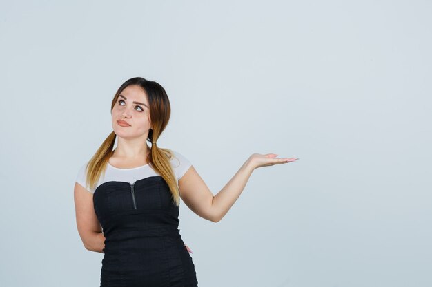 Blonde young lady in dress gesturing isolated