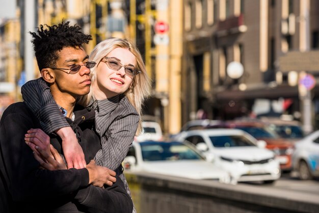 Blonde young woman embracing her boyfriend on city street