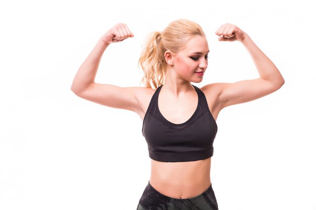 Blonde young woman fitness model in black sports top demonstrates her figure