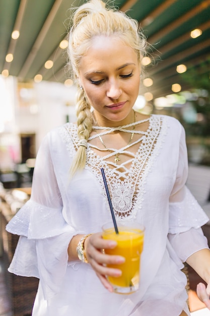 Foto gratuita giovane donna bionda che tiene vetro del succo del mango