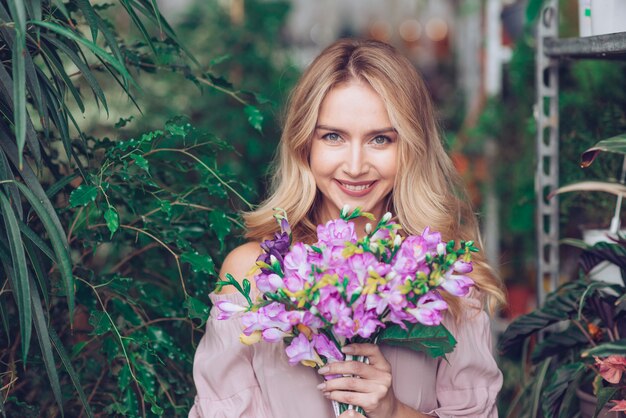 Blonde young woman holding purple flower bouquet in hands