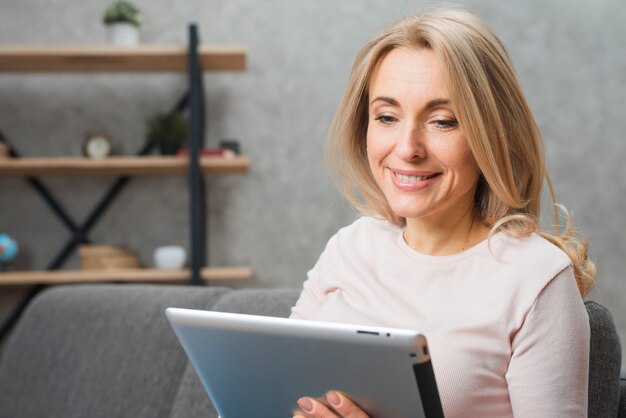 Blonde young woman looking at digital tablet