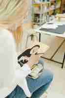 Foto gratuita giovane donna bionda che dipinge lo schizzo che si siede nell'officina