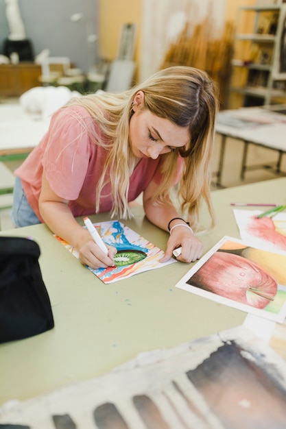 Pittura bionda della giovane donna con l'indicatore sulla tavola