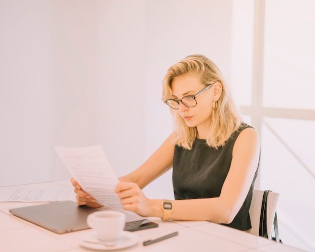 Blonde young woman reading documents at workplace in the office