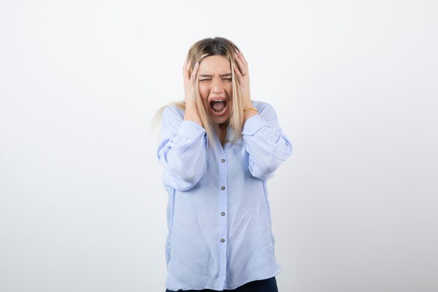 blonde young woman screaming on white background.