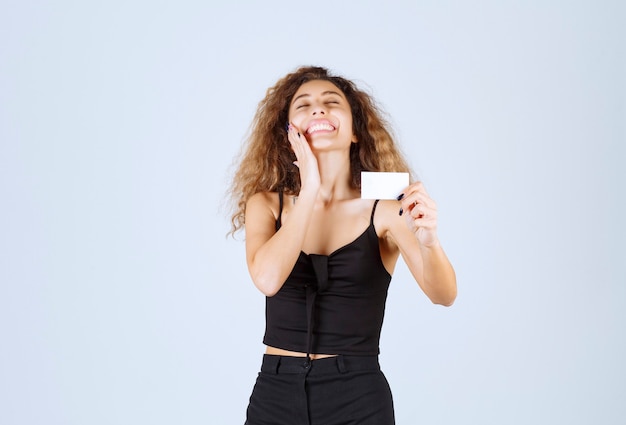 Blondie girl holding a business card and looks surprized. 