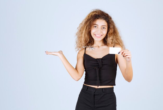 Blondie girl holding a business card and showing her colleague. 